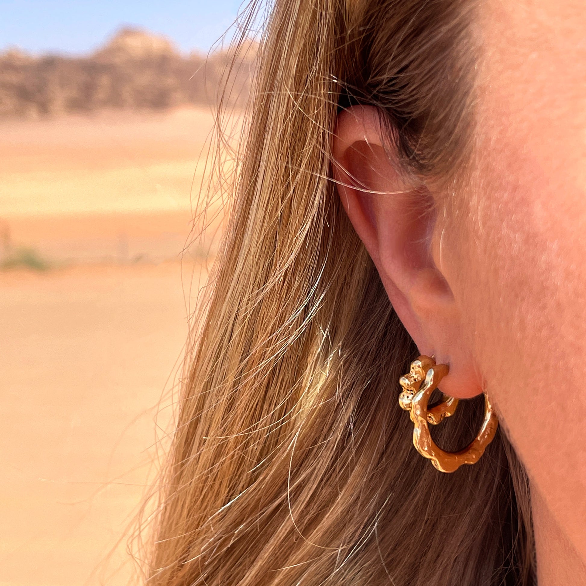 Medium sized gold hoop earrings with organic texture, being worn with smaller textured gold hoop earrings.